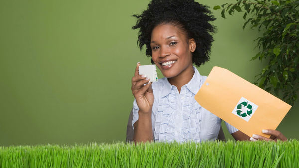 Une femme noire tenant une enveloppe verte devant une pelouse verte.
Mots-clés : recycleur, cartouches d'encre.