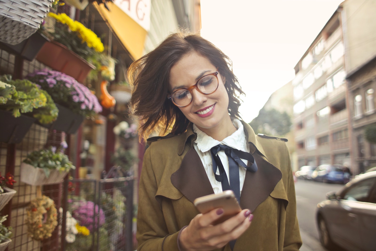 Une femme à lunettes regarde son téléphone dans la rue tout en explorant des programmes de vente de cartouches vides.