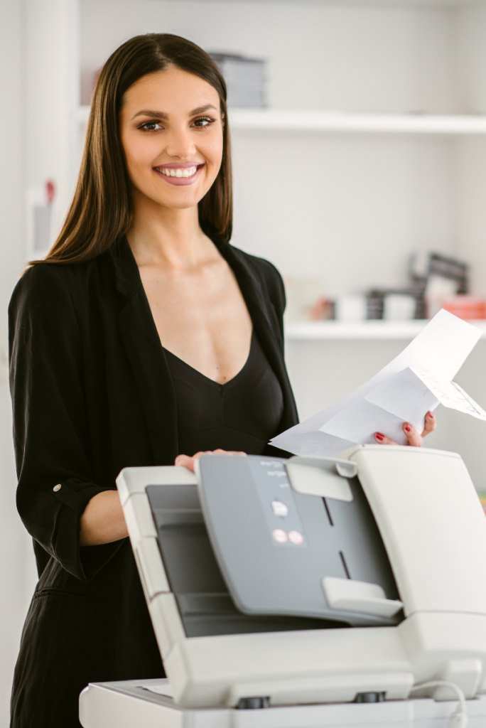 Une femme en costume d'affaires se tient à côté d'une imprimante de systèmes d'impression en continu.