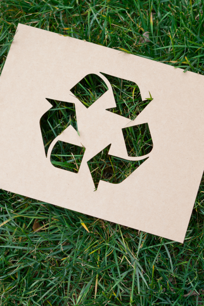 Un morceau de papier recyclable avec un symbole de recyclage dans l'herbe.