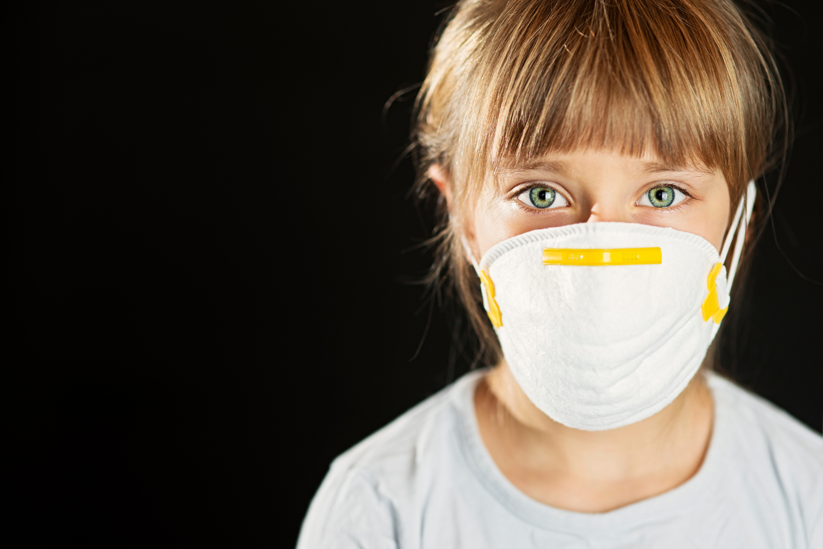 Une fille portant un masque facial sur fond noir, soulignant l'impact de la qualité de l'air.