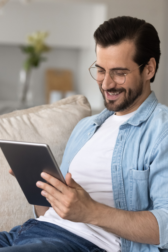 Un homme utilise une tablette alors qu’il est assis sur un canapé.